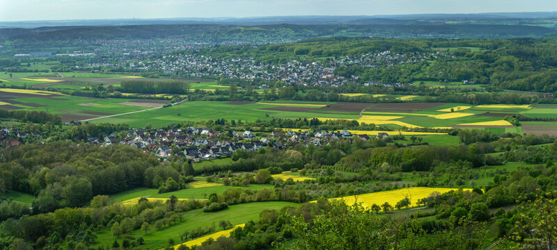 Aerial view of the hills near Walberla, looking towards Forchheim, vibrant yellow rapeseed fields and lush green meadows in the rolling landscape of Bavaria, Germany.