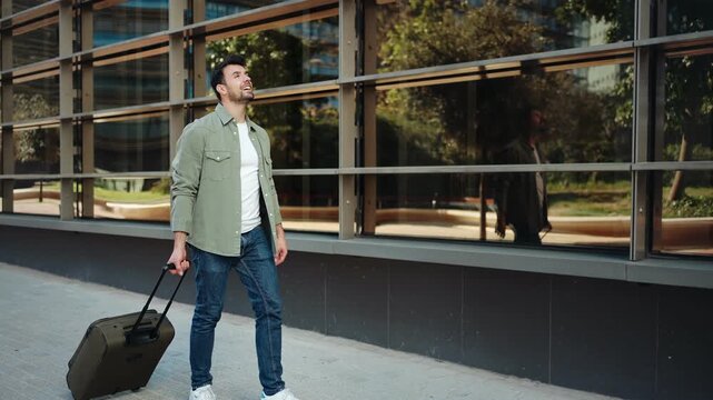 Young man walking in the city, carrying suitcase baggage arriving to hotel. Travel lifestyle