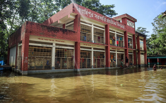 Noakhali, Chittagong Division, Bangladesh - 02 September 2024: View of the flooded Charahipur Government Primary School building with people wading through the water.