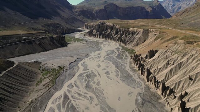 Aerial view of Spiti River valley with braided river channels and steep eroded cliffs in Lahaul and Spiti, Himachal Pradesh, India.