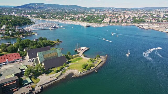 Aerial view of the Bygdoy peninsula in Oslo, featuring the Fram Museum, lush green parks, a marina filled with boats, and the sparkling waters of the Oslofjord, Oslo, Oslo, Norway.