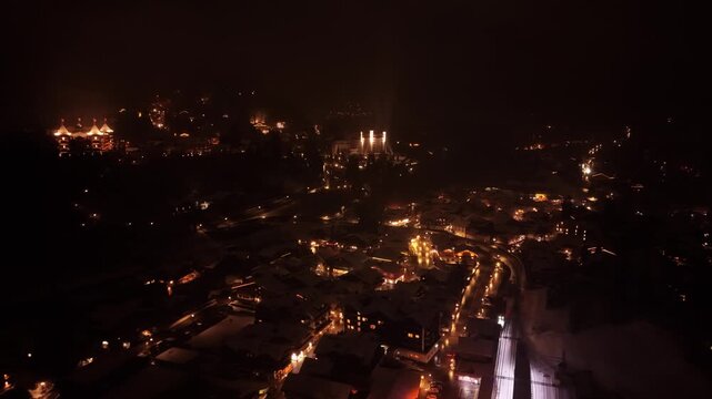 Aerial view of Gstaad at night with illuminated buildings and streets in the town of Saanen, Canton of Bern, Switzerland.
