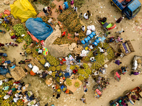 Dhaka, Bangladesh - 06 March 2026: Aerial view of Hazaribag market with vendors selling piles of fresh fruit, people navigating the crowded space, and colorful tarps on the ground.