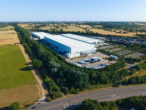 Aerial view of Daventry International Rail Freight Terminal featuring large industrial warehouses and numerous parked HGVs surrounded by rural landscape in Kilsby, England, United Kingdom.