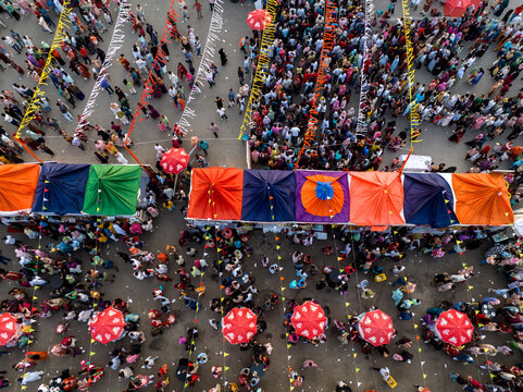 Dhaka, Bangladesh - 17 April 2026: Aerial view of a bustling outdoor market with colorful tents, numerous people walking through the crowded space, and festive bunting decorations.
