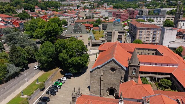 Aerial view of the historic Church of Saint Francis with its stone facade and red-tiled roof, surrounded by urban buildings and trees in Guimaraes, Braga, Portugal.