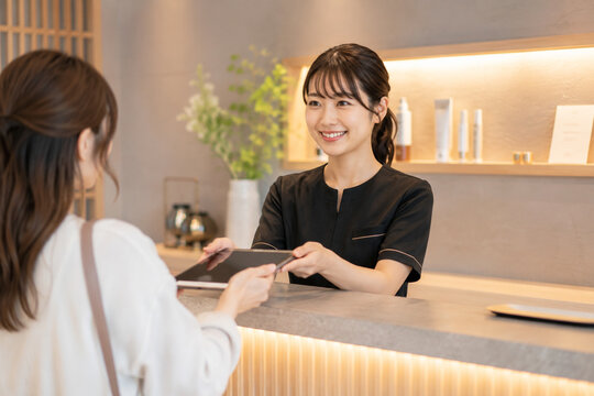 受付でタブレットを見せながら説明する女性スタッフ