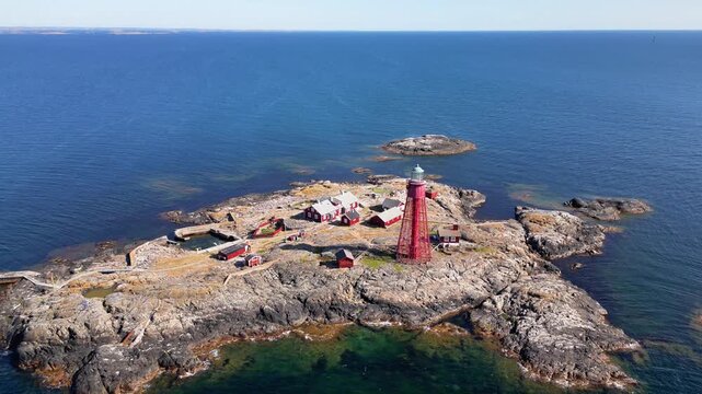 Aerial view of the iconic red Pater Noster Fyr lighthouse situated on a rugged, rocky island surrounded by the deep blue waters of the sea in Kladesholmen, Vastra Gotalands lan, Sweden.