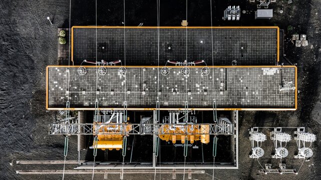 Aerial view of the high voltage station featuring industrial infrastructure, power lines, and electrical equipment on dark gravel ground in Hafnarfjordur, Hafnarfjardarkaupstad, Iceland.