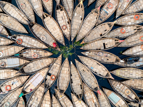 Dhaka, Bangladesh - 20 February 2026: Aerial view of Sadarghat, showing numerous wooden boats arranged in a circular pattern on the Buriganga River, with wooden decks and lifebuoys.