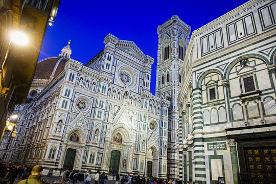 Florence, Italy - 22 April 2017: View of the Cattedrale di Santa Maria del Fiore with its iconic dome and Giotto's Campanile illuminated against the deep blue evening sky.