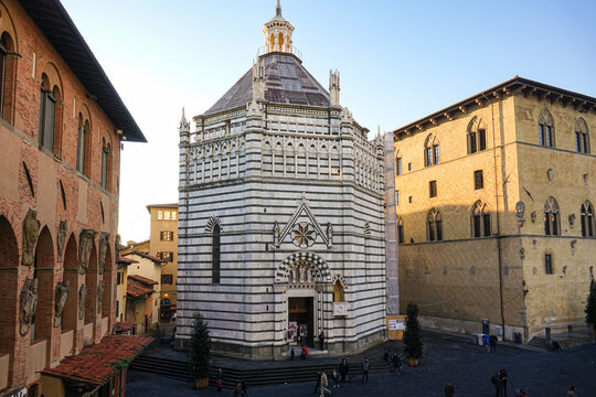 View of the Baptistery of San Giovanni in Corte with its distinctive white and green marble stripes, situated in a historic square in Pistoia, Tuscany, Italy.