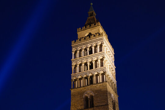 View of the illuminated bell tower of the Pistoia Cathedral with its distinctive striped marble architecture in Pistoia, Tuscany, Italy.