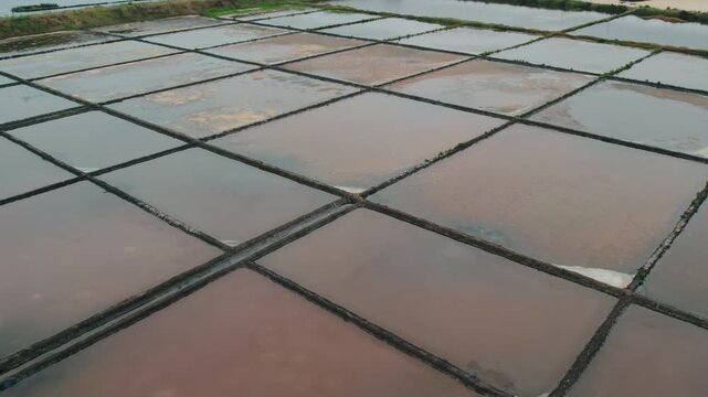 Aerial view of the geometric salt pans of the Aveiro Salt Flats with reflective water surfaces in Aveiro, Aveiro, Portugal.