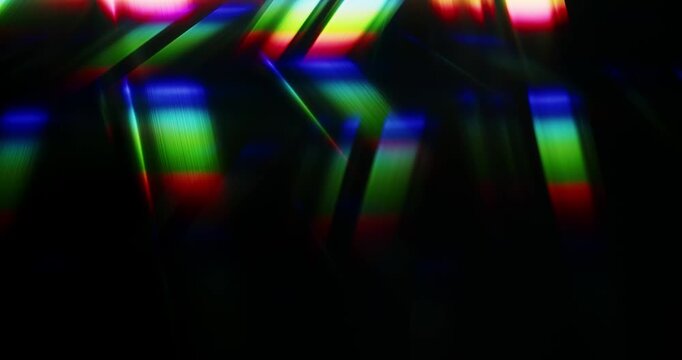 Light rays shining into a glass prism causing an optical effect of a dazzling rainbow of sparkling lights. Reflective streaks of angled lighting creating a visual of brilliant shining colors. Loop.