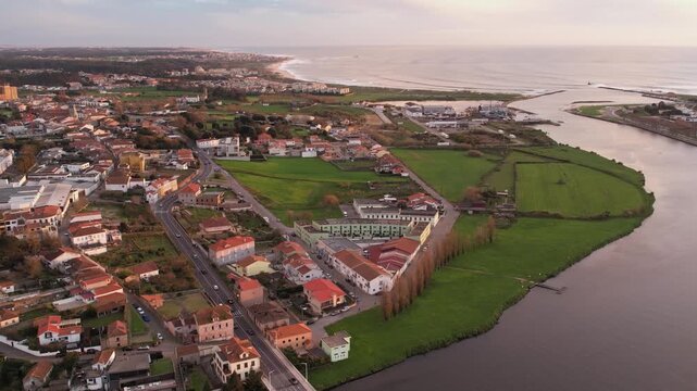 Aerial view of the river Ave flowing past the town with the historic monastery in the distance and a bridge crossing the water in Vila do Conde, Porto, Portugal.