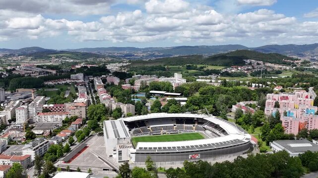 Aerial view of Estadio D. Afonso Henriques stadium surrounded by urban buildings and green hills in Guimaraes, Braga, Portugal.