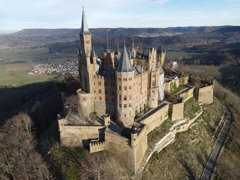 Aerial view of Hohenzollern Castle with its historic towers and stone fortifications set atop a forested hill in Burg Hohenzollern, Baden-Wurttemberg, Germany.