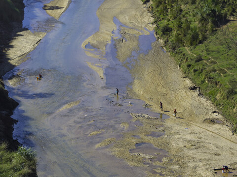 Aerial view of people working in the shallow riverbed of the Dajabon river with sandy banks and green vegetation in Dajabon, Dajabon Province, Dominican Republic.