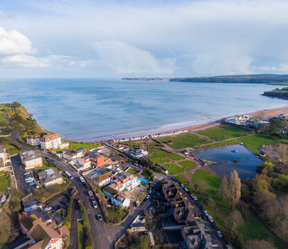 Aerial view of the coastal town of Paignton with its sandy beach, green parkland, and residential buildings along the shoreline in Paignton, England, United Kingdom.