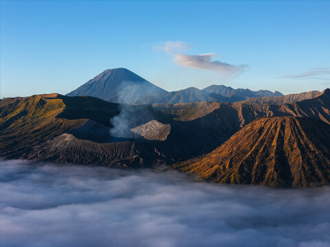 Aerial view of Mount Bromo and the volcanic landscape rising above a sea of clouds in the morning light near Seruni Point in Sukapura, East Java, Indonesia.