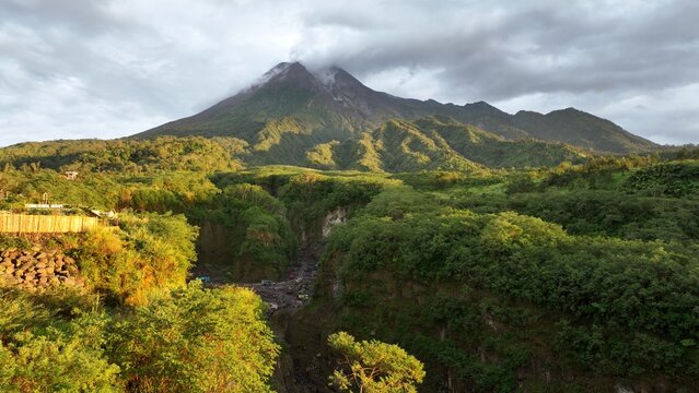 Aerial view of Mount Merapi surrounded by lush green vegetation and volcanic landscape in Kecamatan Cangkringan, Daerah Istimewa Yogya, Indonesia.