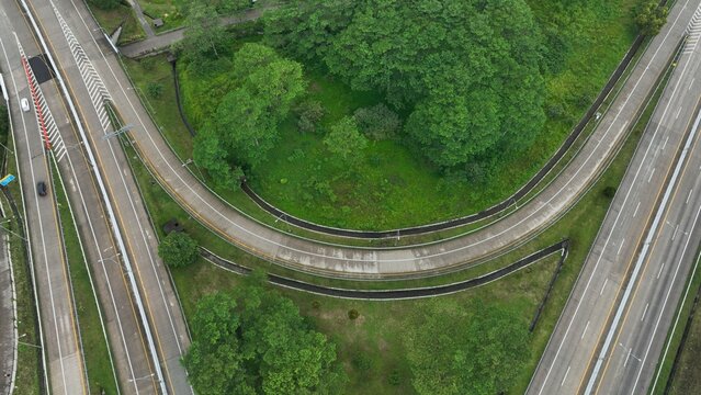Aerial view of the highway interchange in Parungkuda, featuring curved road sections, lush green vegetation, and surrounding trees in Parungkuda, West Java, Indonesia.