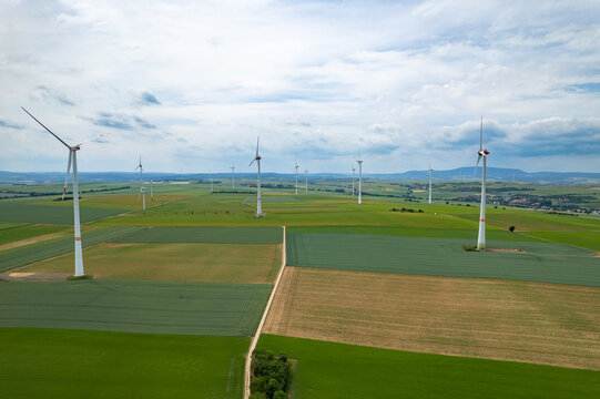 Aerial view of wind turbines standing in green agricultural fields under a cloudy sky in Worms, Rhineland-Palatinate, Germany.