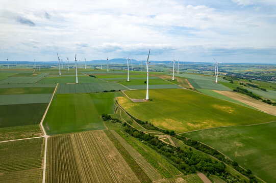 Aerial view of wind turbines in a rural landscape with green fields and vineyards in Worms, Rhineland-Palatinate, Germany.