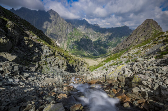 View of the rocky Litvorova dolina with a flowing mountain stream, steep peaks, and green slopes in Tatranska Javorina, Presovsky kraj, Slovakia.