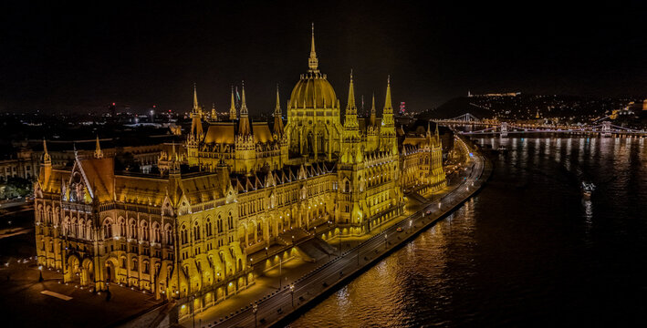 Aerial view of the illuminated Hungarian Parliament Building at night along the Danube river in Budapest, Hungary.