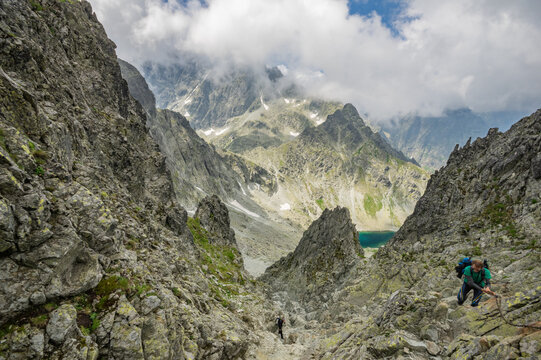 Tatranska Javorina, Slovakia - 22 July 2016: View of Sedlo Prielom with hikers navigating the steep rocky mountain pass under a cloudy sky.