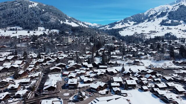 Aerial view of Gstaad Palace overlooking the snow-covered village of Saanen with traditional wooden chalets nestled in the Bernese Alps, Saanen, Bern, Switzerland.