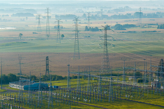 Aerial view of an electrical substation with high-voltage power lines stretching across a rural landscape in Poland.