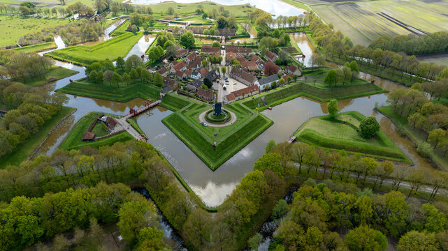 Aerial view of the star-shaped Bourtange Fortress Museum with its historic buildings, surrounding moats, and lush green ramparts in Bourtange, Groningen, Netherlands.