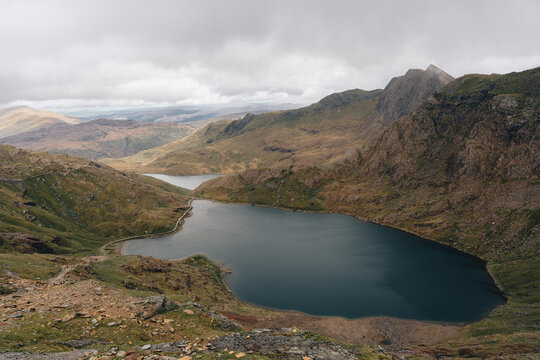 View of Y Lliwedd mountain rising above the dark waters of Llyn Llydaw in the rugged landscape of Snowdonia, Caernarfon, Wales, United Kingdom.