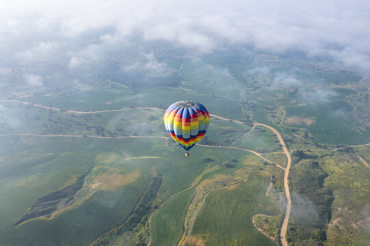 Aerial view of a colorful hot air balloon floating above the lush green fields and dirt roads of Kibbutz Ruhama, South District, Israel.
