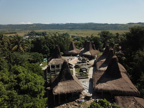 East Nusa Tenggara, Indonesia - 17 July 2026: Aerial view of Prai Ijing traditional village of Sumba with iconic high-pitched thatched roofs surrounded by lush tropical trees and open fields.