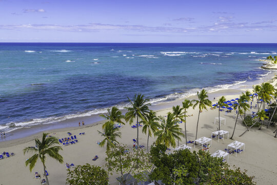 Aerial view of Playa Dorada beach with turquoise waters, white sand, palm trees, and beach umbrellas in Puerto Plata, Puerto Plata Province, Dominican Republic.