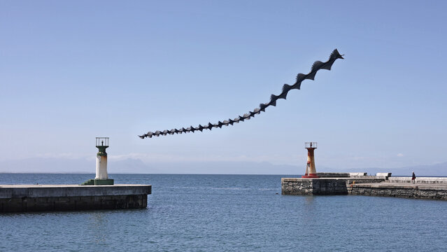 View of a chronophoto of a cormorant in flight over the harbor with two lighthouses in Cape Town, Western Cape, South Africa.