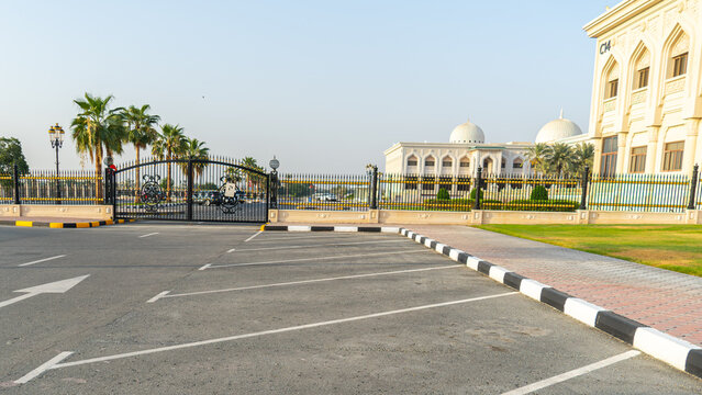 View of the University of Sharjah campus featuring traditional Islamic architecture with domes, palm trees, and a gated entrance near a parking lot in Sharjah, Sharjah, United Arab Emirates.