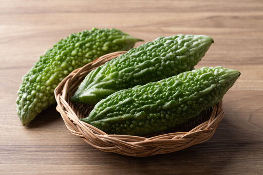 Fresh bitter gourd or bitter melon in a basket on a wooden background, Asian vegetables and herbal medicine