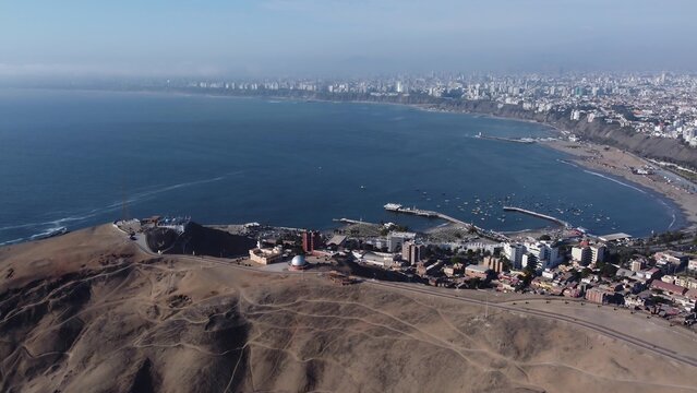 Aerial view of Chorrillos district with its coastal bay, small boats, urban buildings, and arid landscape in Lima, Lima, Peru.