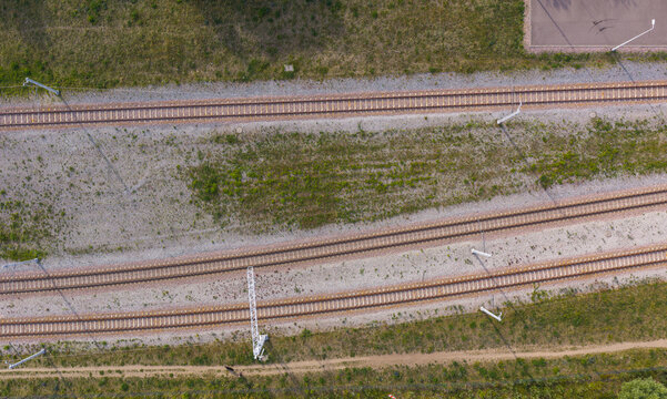 Aerial view of parallel railway tracks with gravel ballast and surrounding green vegetation in Gdansk, Pomeranian Voivodeshi, Poland.