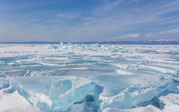 View of the frozen surface of Lake Baikal with large transparent ice blocks under a clear blue sky in Khuzhir, Irkutsk Oblast, Russia.