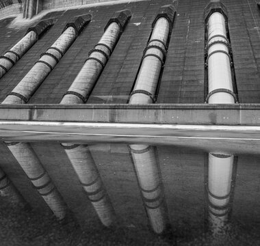 View of the industrial penstocks of the Revelstoke Dam reflecting in the water below in Revelstoke, British Columbia, Canada.