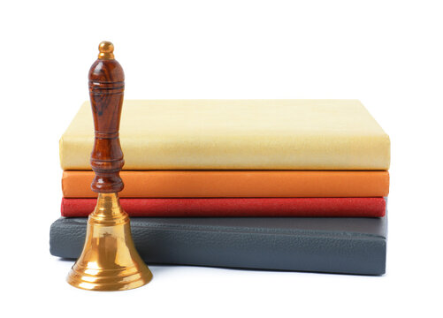 Golden school bell and stack of books isolated on white