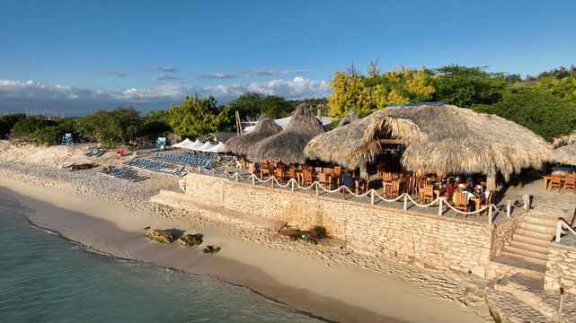 Aerial view of Cueva de Las Aguilas restaurant with thatched roofs and wooden furniture along the sandy coastline in Poblado de la Cueva de los Pescadores, Pedernales, Dominican Republic.
