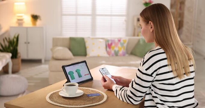 Online store. Woman with credit card using tablet and smartphone at wooden table indoors, back view