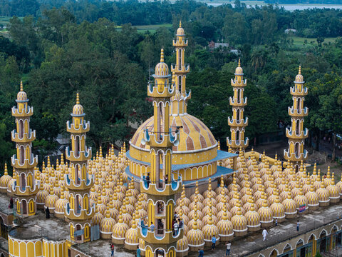 Tangail District, Bangladesh - 17 July 2026: Aerial view of 201 Gombuj Masjid, a unique mosque with a large central dome, numerous smaller golden domes, and tall minarets amidst lush trees.